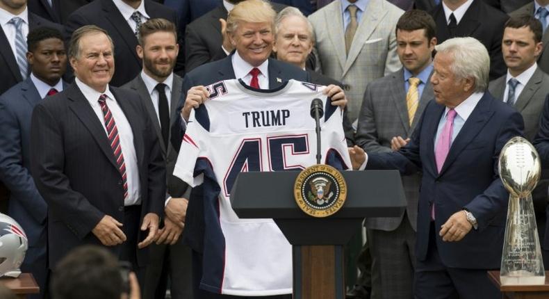 US President Donald Trump holds a jersey given to him by New England Patriots owner Robert Kraft (R) and head coach Bill Belichick (L) alongside members of the team during a ceremony at the White House in April 2017