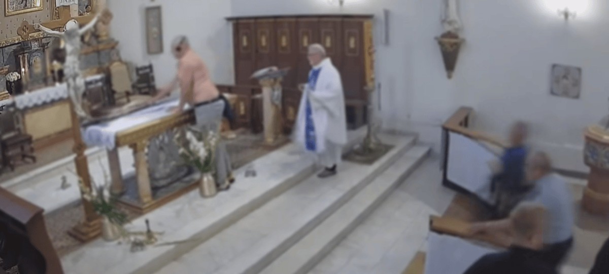 Półnagi mężczyzna demoluje ołtarz w kościele podczas mszy w Mieścisku, obok stoi ksiądz w białych szatach liturgicznych, a wierni reagują z ławek.
