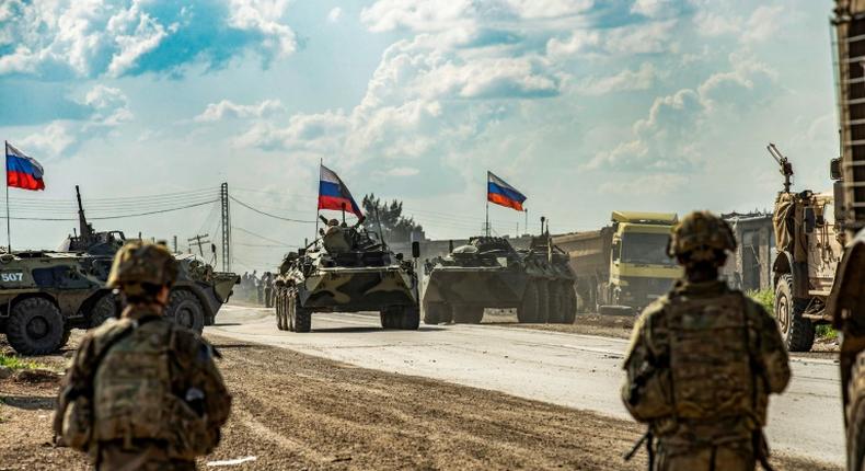 US soldiers stand along a road across from Russian military armored personnel carriers near the village of Tannuriyah in Syria's northeastern Hasakah province on May 2, 2020