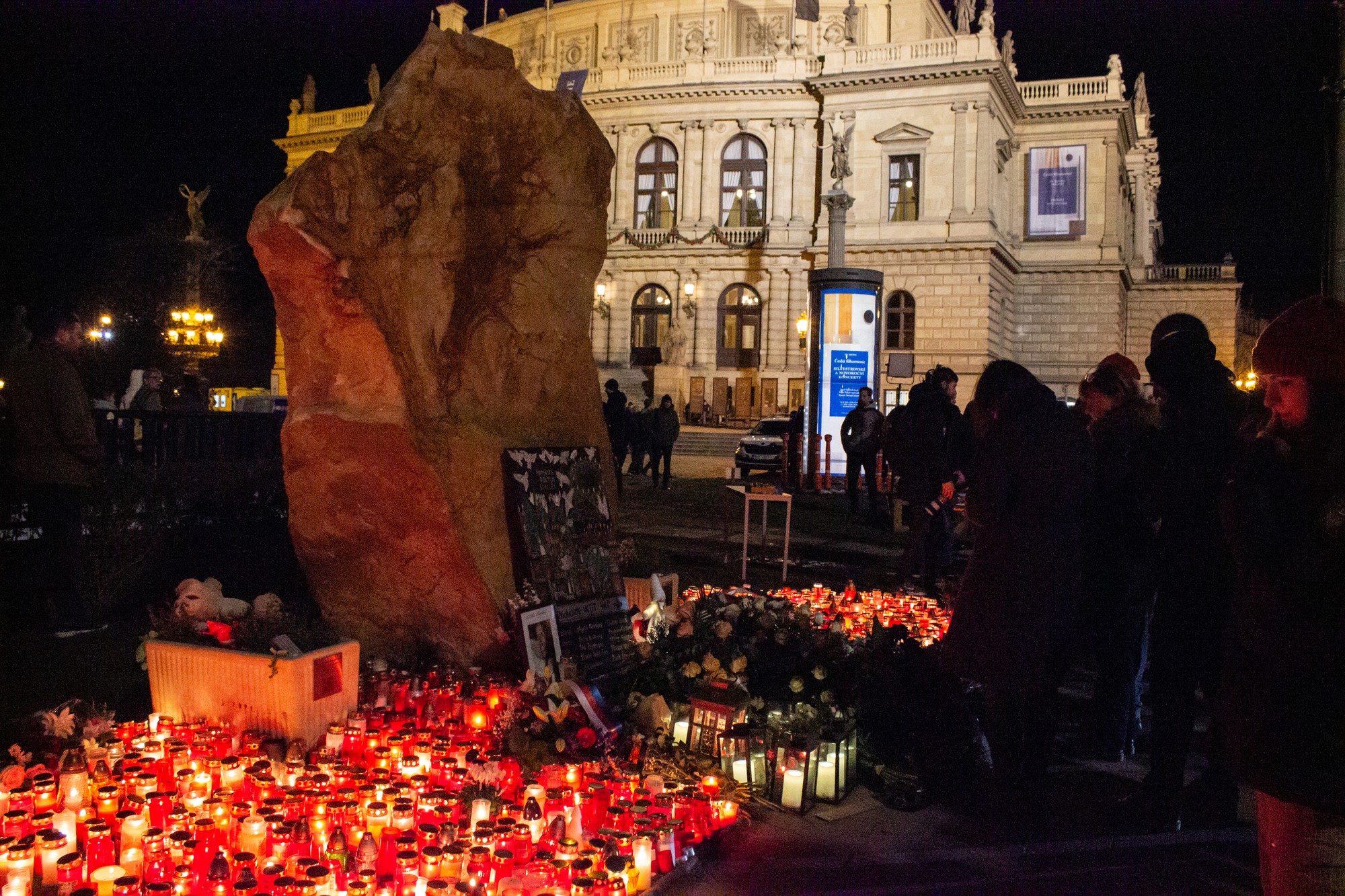 Na snímke ľudia zhromaždení pred pamätníkom obetí streľby z 21. decembra 2023 pred budovou Filozofickej fakulty Univerzity Karlovej počas pietnej spomienky v deň prvého výročia.