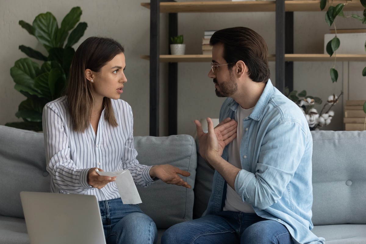 Kobieta i mężczyzna rozmawiają ze sobą, siedząc na kanapie i gestykulując