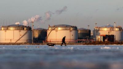 A fisherman carries his belongings on a sleigh on the ice of the Gulf of Finland against the backdrop of the St. Petersburg Oil Terminal in St. Petersburg.SOPA Images via Getty