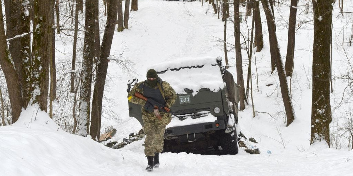 Członek Ukraińskich Sił Obrony Terytorialnej przechodzi obok zniszczonych rosyjskich pojazdów wojskowych w lesie pod Charkowem.