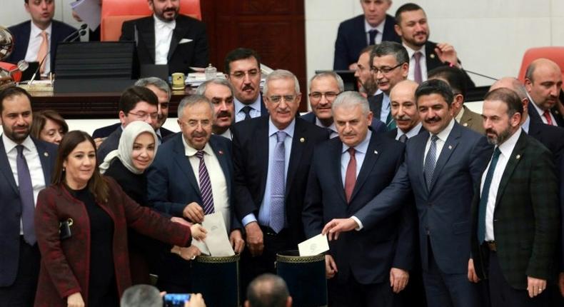 Turkish Prime Minister Binali Yildirim (3rd R) and lawmakers pose as they cast their ballots during a vote on provisions in a bill to change the constitution at the Turkish parliament in Ankara on January 14, 2017