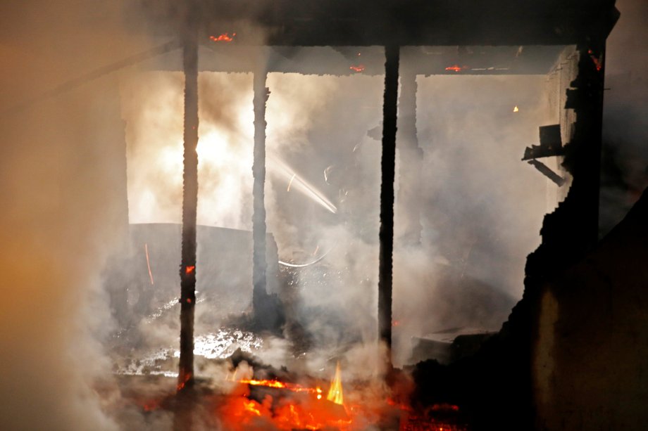 Firefighters extinguish shelters during a big fire which destroyed many wood houses at a camp for migrants in Grande-Synthe near Dunkirk, France, April 11, 2017.