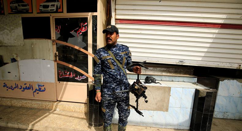 A member of the Iraqi federal police carries a destroyed drone belonging to ISIS militants, in Mosul, March 19, 2017.