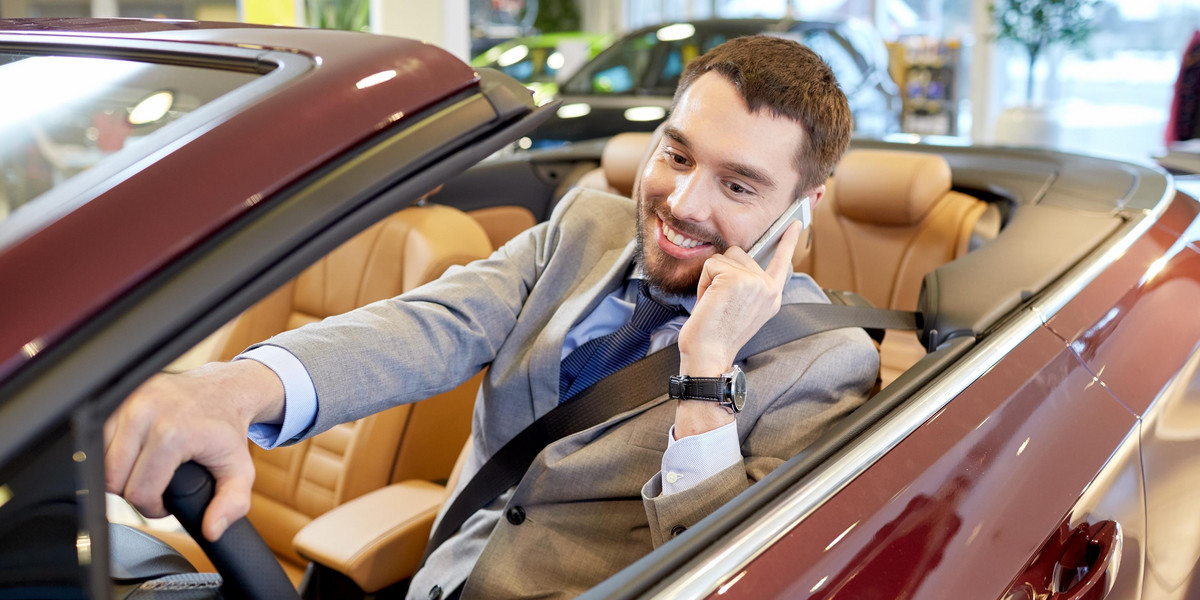 happy man sitting in car at auto show or salon