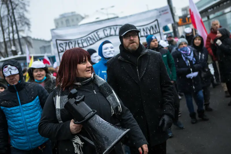 Poseł Grzegorz Braun maszeruje tuż przed znakiem &quot;Szczepienie czyni wolnym&quot;, styczeń 2021