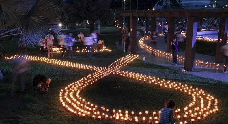 Volunteers light up candles in the shape of an HIV/AIDS awareness Red Ribbon during the International AIDS Candlelight Memorial in San Salvador May 17, 2015. REUTERS/Jose Cabezas/Files