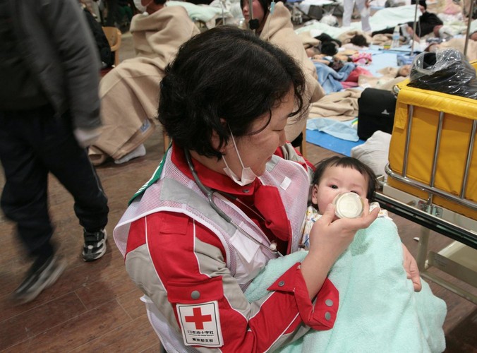 Pracownica Czerwonego Krzyża karmi niemowlaka w szpitalu w Ishinomaki w prefekturze Miyagi