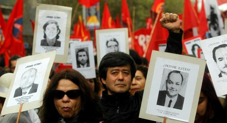 Human rights activists hold pictures of missing people during a march in Santiago, in September 2016, commemorating the 43rd anniversary of the military coup led by General Augusto Pinochet that deposed President Salvador Allende