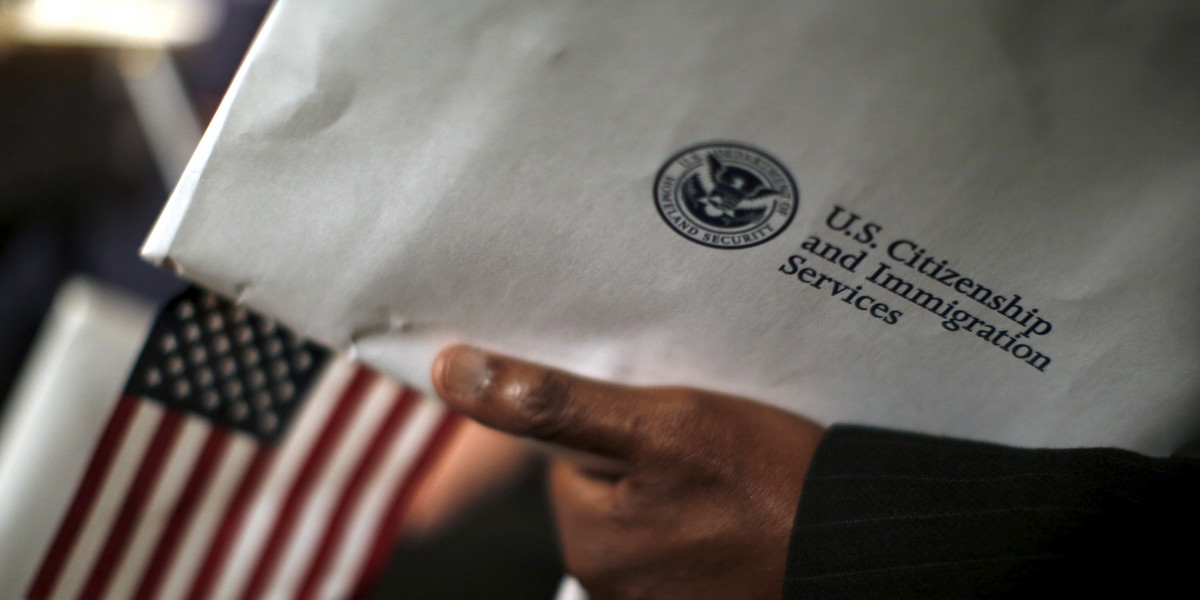 A man holds an envelope from US Citizenship and Immigrations Services during a naturalization ceremony at the National Archives Museum in Washington, DC, on December 15, 2015.