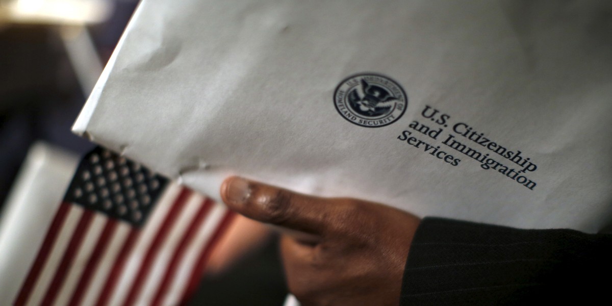 A man holds an envelope from US Citizenship and Immigrations Services during a naturalization ceremony at the National Archives Museum in Washington, DC, on December 15, 2015.