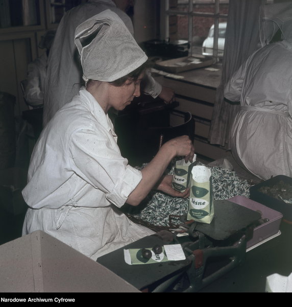 Kobieta pakująca cukierki "Leśne - łagodzą kaszel" do papierowej torebki. Fabryka Cukrów i Czekolady "Ślązak" w Raciborzu - 1970 rok-  - Narodowe Archiwum Cyfrowe