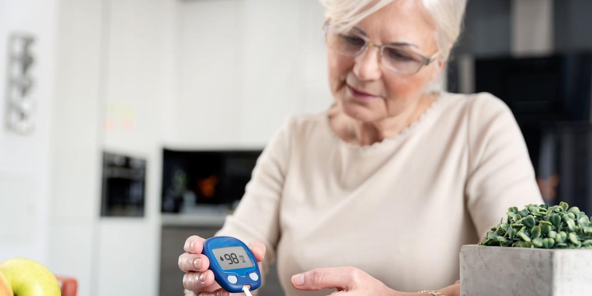 Senior woman checking blood sugar level at home