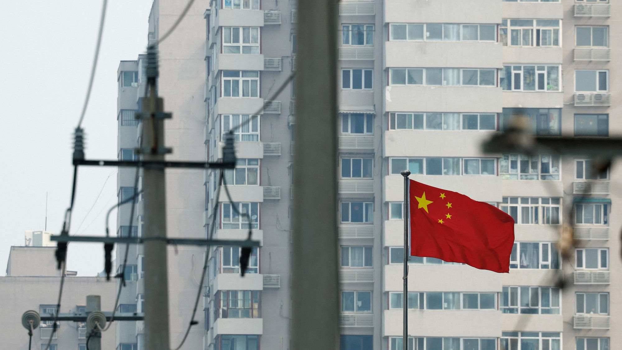 Čínska štátna vlajka v blízkosti obytných budov v Pekingu, REUTERS/Tingshu Wang