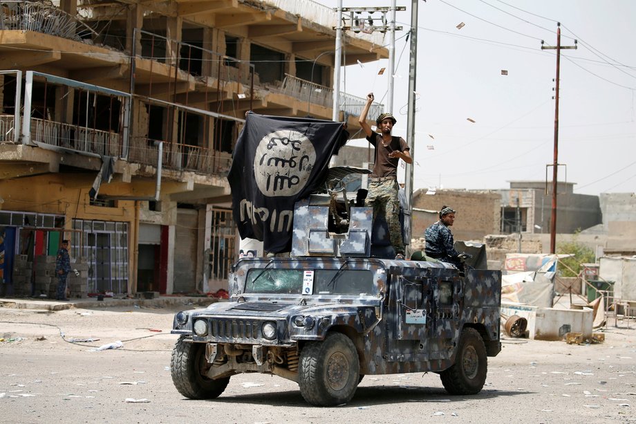 Members of Iraqi government forces celebrate on a street in Fallujah after government forces recaptured the city from ISIS militants on June 27.