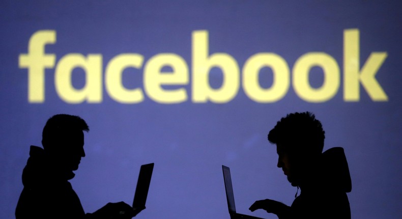 FILE PHOTO: Silhouettes of laptop users are seen next to a screen projection of Facebook logo in this picture illustration taken March 28, 2018. REUTERS/Dado Ruvic/Illustration/File Photo