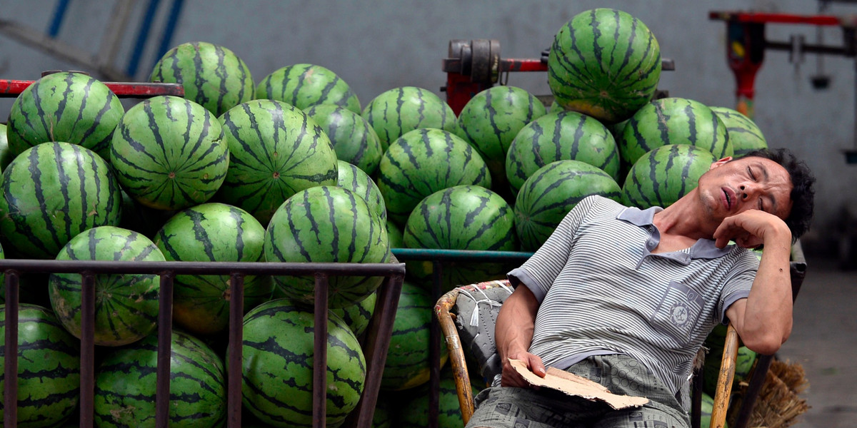 A vendor selling watermelons naps as he waits for customers at a market in Taiyuan, Shanxi province, July 17, 2013.