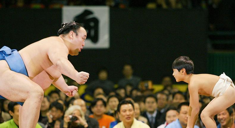 A Japanese sumo wrestler plays with children before the opening ceremony of a sumo tournament at the Changchung gymnasium on February 14, 2004, in Seoul, South Korea. Wrestlers arrived on friday, for their first tournament in South Korea since the country was released from Japanese colonial rule in 1945.