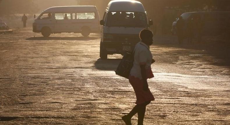 A woman crosses the street in front of minibus taxis in Harare, Zimbabwe, August 31, 2016.   REUTERS/Philimon Bulawayo