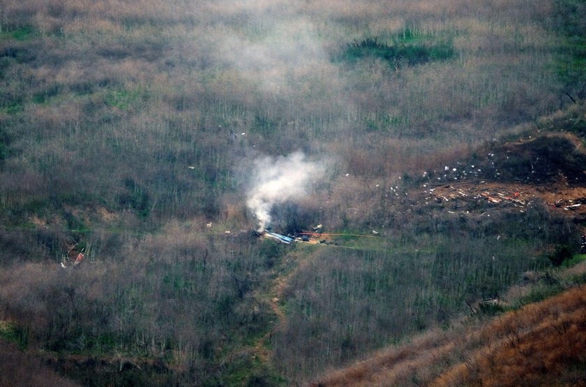 People watch as smoke rises from the scene of a helicopter crash that reportedly killed retired bask