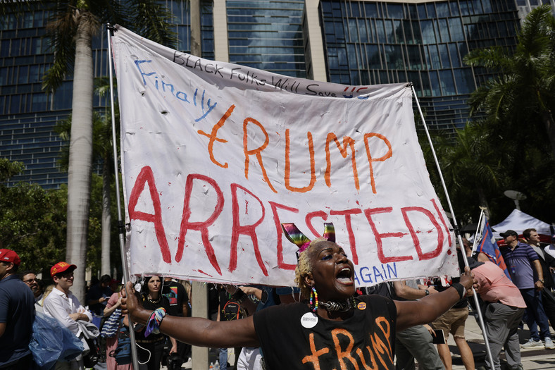Przeciwniczka Trumpa Nadine Seiler trzymająca transparent z napisem: "Wreszcie Trump ponownie aresztowany" przed budynkiem Sądu Federalnego Stanów Zjednoczonych, 13 czerwca 2023 r.