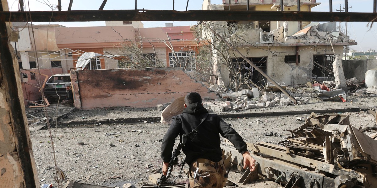 An Iraqi special forces soldier runs across a street after an Islamic State suicide car bomb attack during gunfight in Tahrir neighborhood of Mosul, Iraq, November 17, 2016.