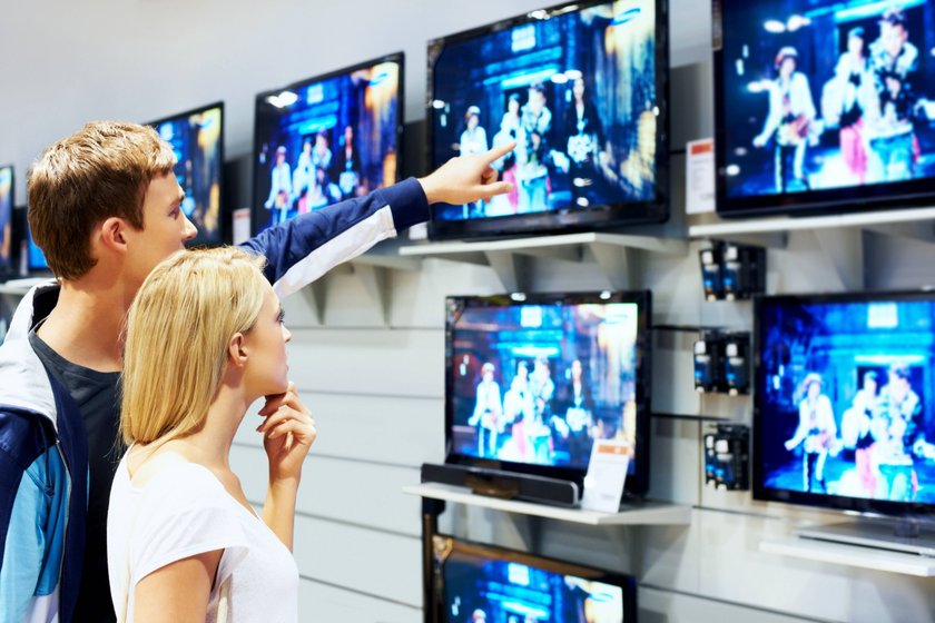 Young couple in megastore looking at TVs