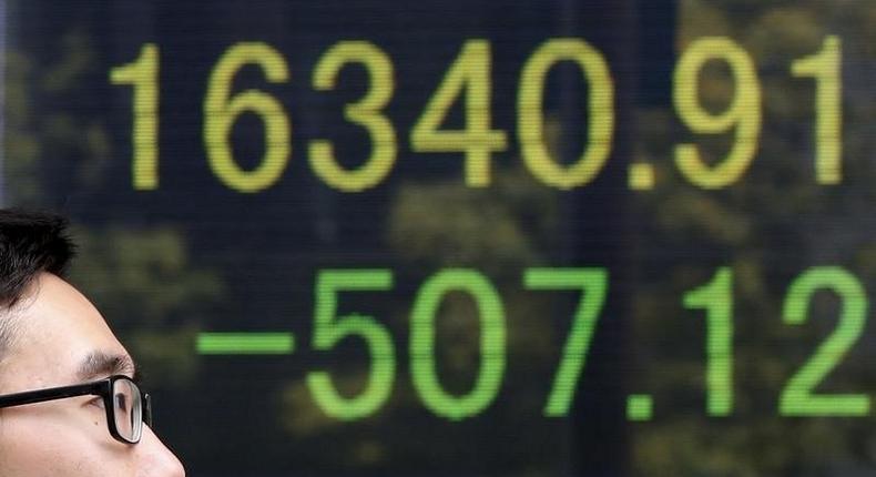 A man walks in front of an electronic board showing Japan's Nikkei average outside a brokerage in Tokyo, Japan, April 18, 2016. 