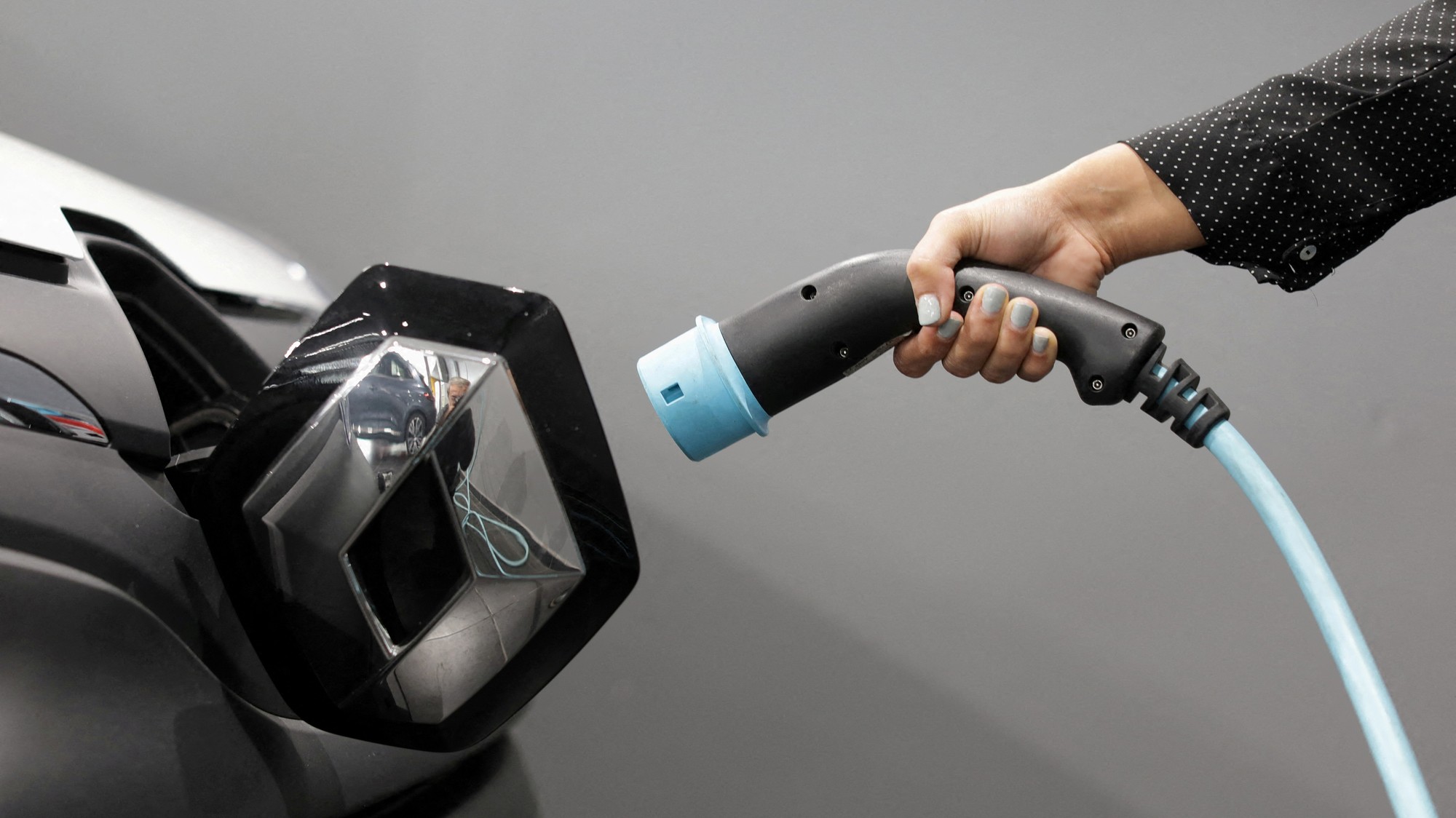 Žena drží kábel na nabíjanie elektromobilu