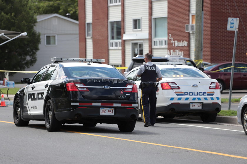 Fredericton residents pay their respects at a makeshift shrine in front of police headquarters