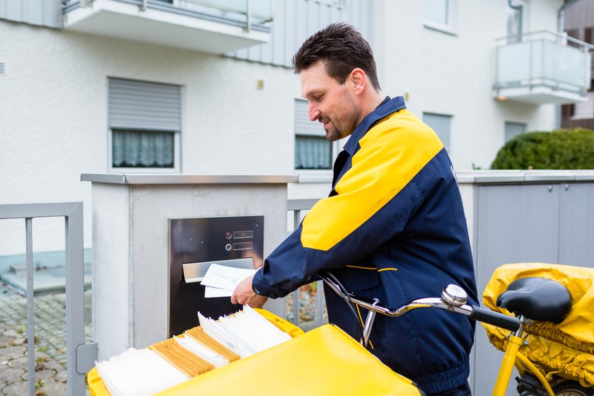 Postman delivering letters to mailbox of recipient