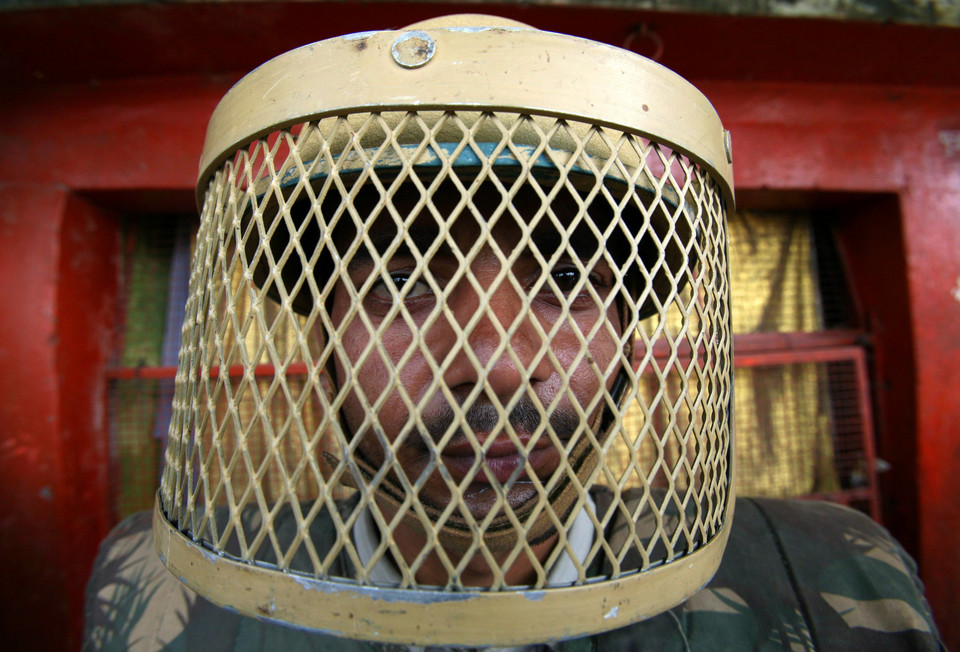 A paramilitary trooper wearing a riot gear stands guard on a road in the northern Indian town of Ayodhya