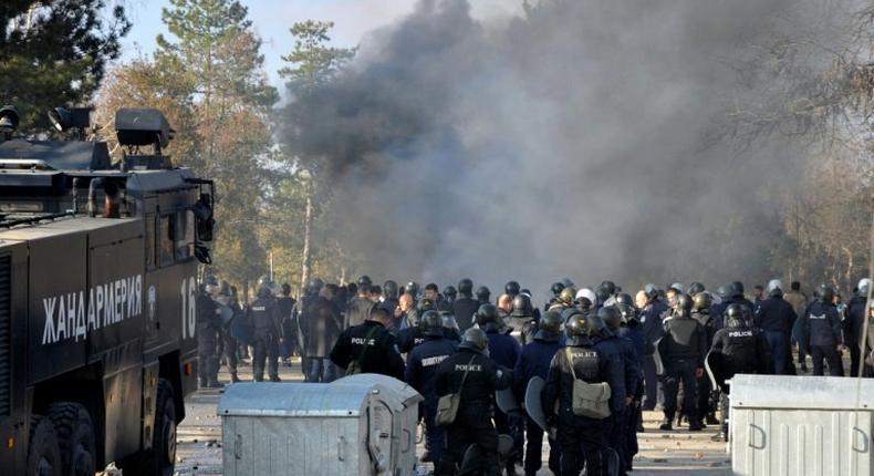 Bulgarian riot police stand near garbarge bins during clashes in the migrants reception centre in the town of Harmanli on November 24, 2016