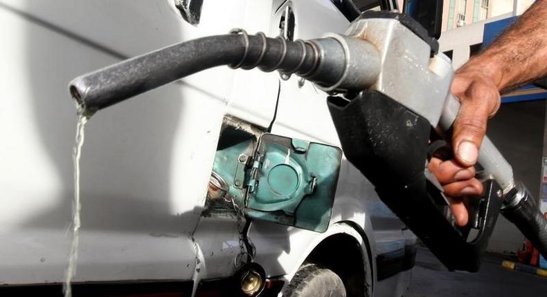 A worker fills the tank of a car at a petrol station.