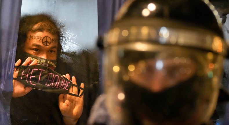 A detained demonstrator shows a sign 'No War!' from a police bus in St. Petersburg, Russia, Thursday, Feb. 24, 2022.