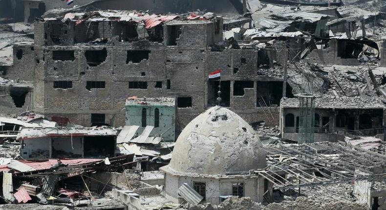 A picture taken on July 9, 2017 shows an Iraqi flag flying from the top of the dome of a badly damaged building