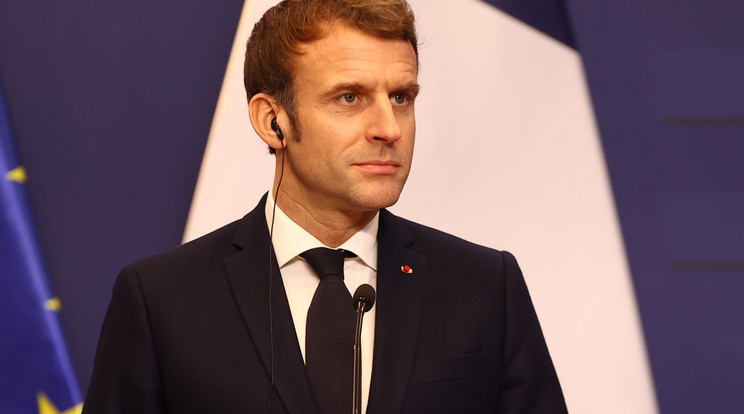 Macron sajtótájékoztatót tart. Csak egészen közelről látszik, hogy az élénkpiros kitűző rózsa- szirom-kompozíció, a sötét zakón igen feltűnő/Fotó: Pozsonyi Zita
