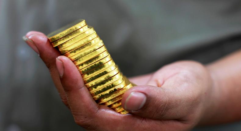 An employee holds gold pieces, each weighing 100 grams, at the state-owned mining company PT Antam Tbk metal refinery in Jakarta, July 13, 2012.REUTERS/Beawiharta
