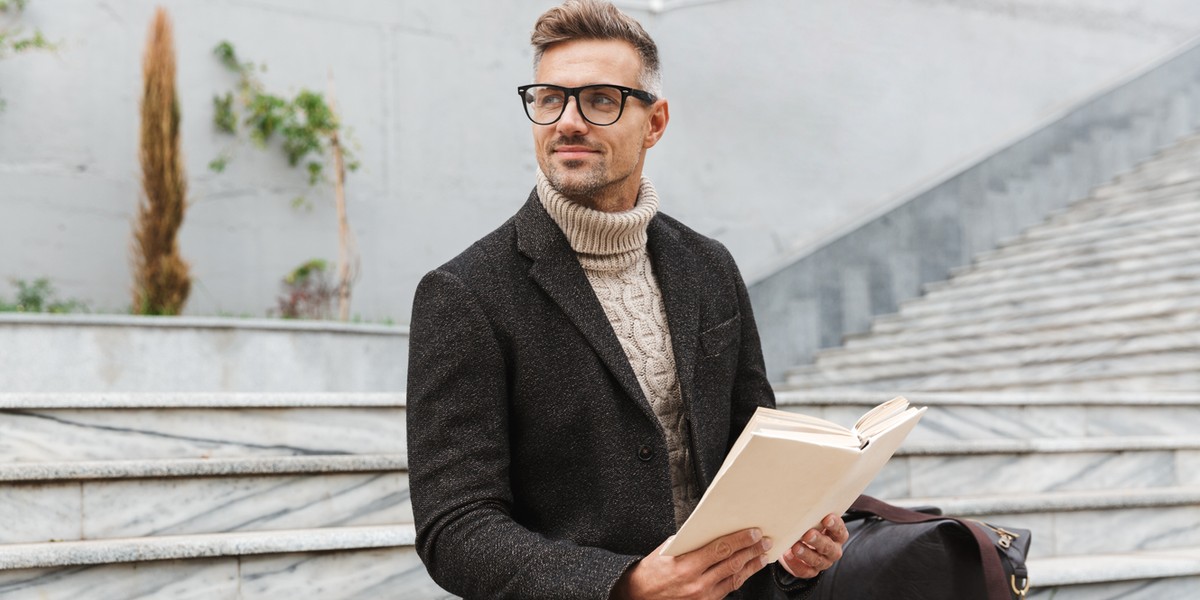 Handsome man wearing jacket reading a book