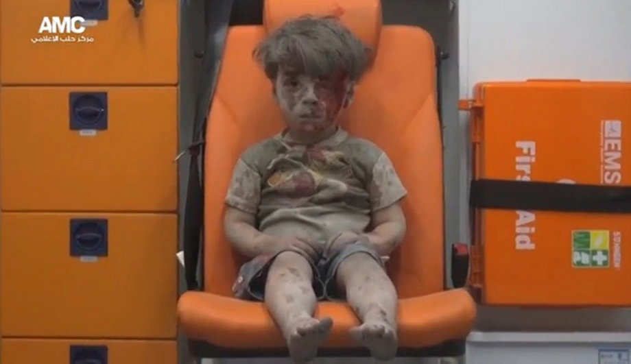 A still image from a video posted on social media shows a boy with bloodied face sitting in an ambulance, after an airstrike