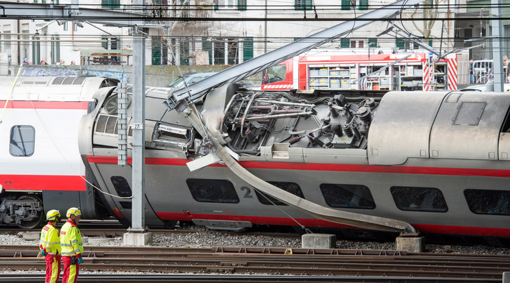 Az EuroCity vasúttársaság Milánó és Bázel között közlekedő járatának kisiklott szerelvényét nézik vasúti dolgozók, miután evakuálták a vonat utasait a svájci Luzern pályaudvarán - Fotó: MTI