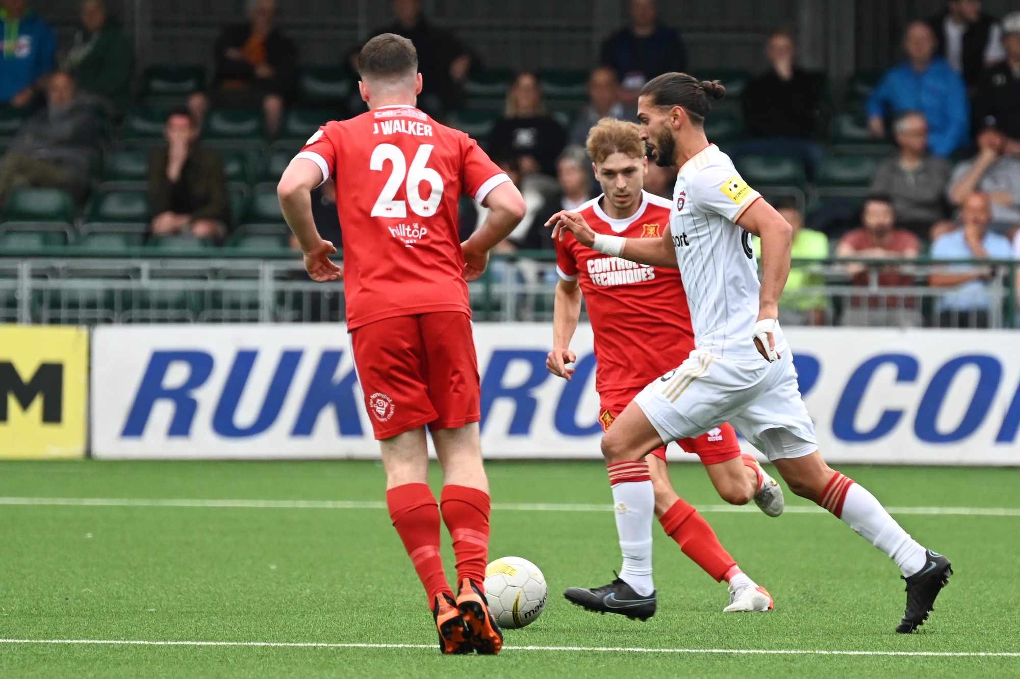 Zľava hráči Newtownu Jake Walker, Henry Cowans a hráč Spartaka Kyriakos Savvidis.