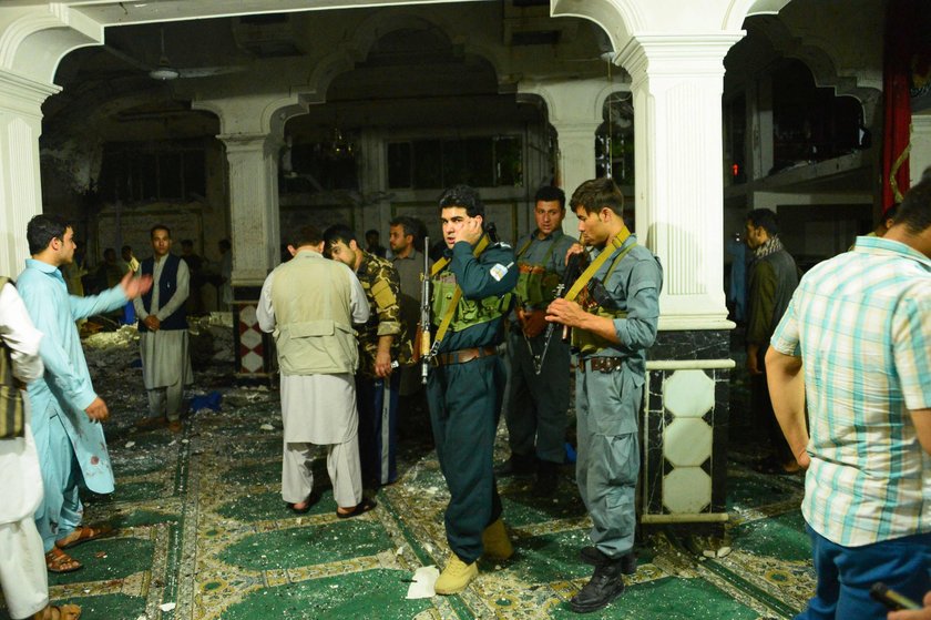 Afghan policemen and relatives inspect at the site of a suicide attack in Herat, Afghanistan