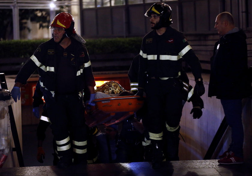 Fire fighters and medical staff member carry an injured person outside the underground where some of