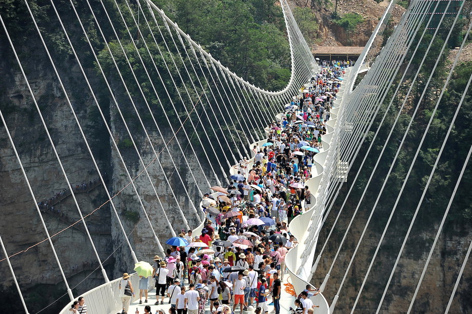 Visitors cross the Zhangjiajie Grand Canyon Glass Bridge on August 20, 2016
