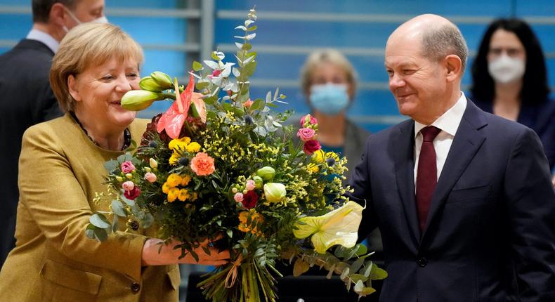 Merkel receives a bouquet from acting German Finance Minister Olaf Scholz on November 24, 2021.