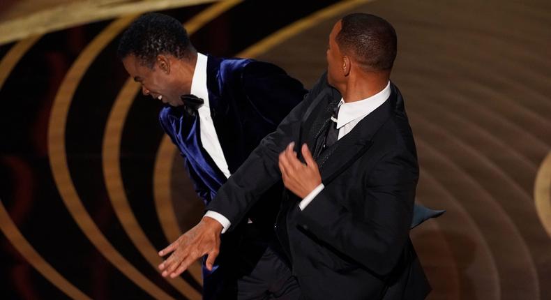 Will Smith, right, hits presenter Chris Rock on stage while presenting the award for best documentary feature at the Oscars on Sunday, March 27, 2022, at the Dolby Theatre in Los Angeles.