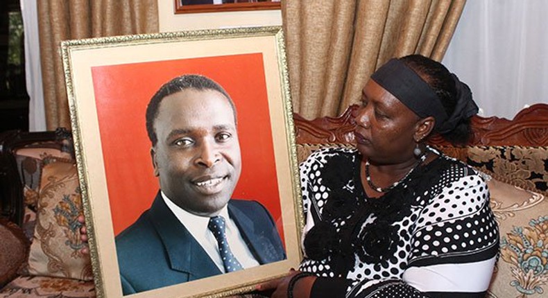 Jonathan Moi's widow Sylvia Toroitich Moi holding the portrait of the deceased at their home in Kabimoi Farm